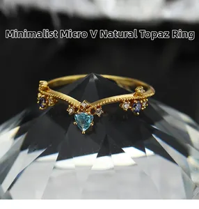 Macro-opname van V-vormige gouden ring met blauwe topaas op kristallen voet