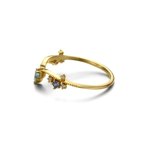 Detail van 925 sterling zilveren gouden ring met blauwe topaas en gegolfde kralenband