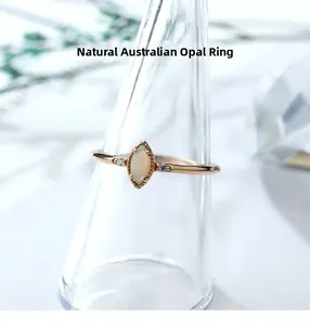 Macro view of marquise cut white opal ring with small side diamonds on a glass stand