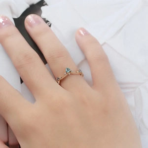 Gedetailleerde close-up van een V-vormige kroonring met lichtblauwe topaas aan de hand van model