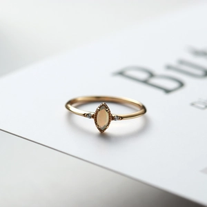 Macro shot of marquise-cut opal ring in gold finish with side diamond accents