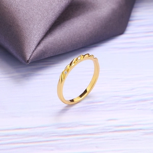 Detalle de anillo dorado ondulado con circonitas sobre fondo violeta suave