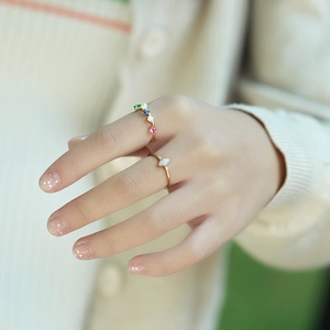 Macro shot of gold-plated silver rings with opal and colorful gemstones on a finger