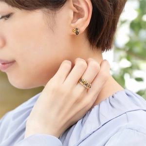 Modelo asiática luciendo elegantes anillos y pendientes dorados con cristales ámbar y café