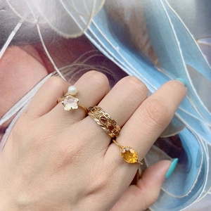 Detalle de anillos apilados en oro 14K con cuarzo rosa, perlas y piedras amarillas