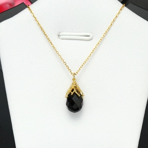 Detail van de zwarte onyx hanger met gouden opengewerkt filigraan en bijpassende ketting