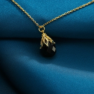 Macro-opname van een 925 zilveren druppelvormige zwarte onyx hanger op zijden stof