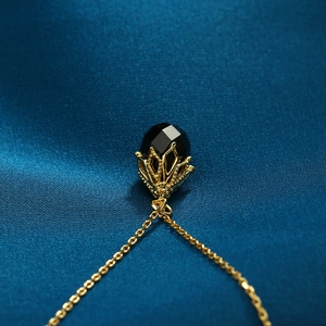 Detail van een gouden ketting met een gefacetteerde hanger van zwarte agaat