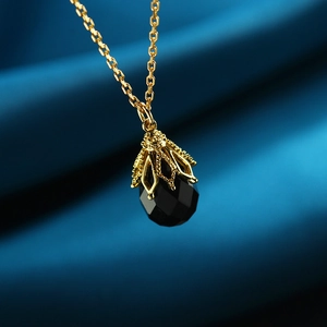 Macro-opname van zwarte onyx hanger met gouden filigraan op blauwe zijden stof