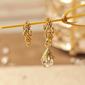 Detailopname van vintage gouden oorbellen met waterdruppel hanger op houten tak