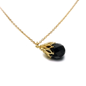 Detail van een vintage ketting met zwarte onyx hanger en gouden krooninstelling