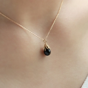 Macro-opname van een zwarte onyx hanger met gouden kantwerk gedragen op de nek van de vrouw