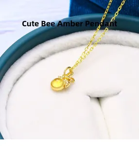 Close-up of golden bee pendant necklace featuring a polished amber stone inlay