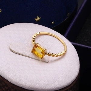 Gelber Kristallring mit goldener Gittermuster-Bandschiene auf blauem Samtdisplay