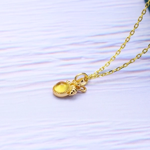 Macro shot of bee-shaped gold S925 silver pendant with amber stone on a gold chain