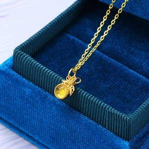 Macro shot of gold bee pendant necklace with amber stone on dark blue velvet box
