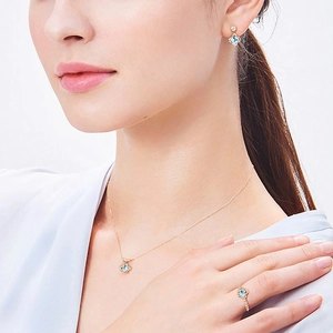 Close-up of 925 silver blue topaz clover necklace, earrings and ring set on model