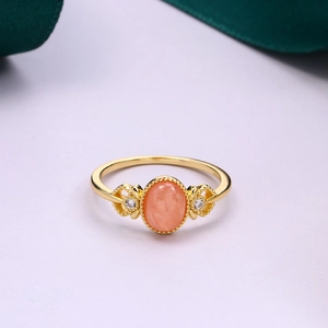 Macro dettaglio di un anello vintage dorato con pietra ovale rosa e decori eleganti