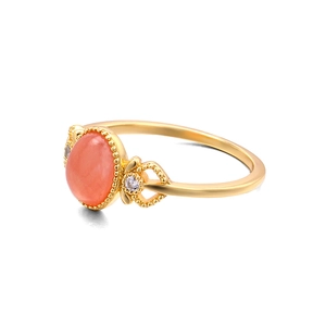 Dettaglio di un anello d'oro vintage con pietra rosa ovale e design a cuore traforato