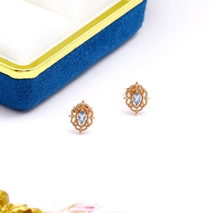 Primer plano de pendientes de oro rosa con piedras de topacio azul talla marquesa