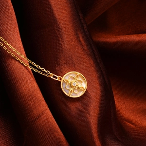 Detailaufnahme der goldenen Kleeblatt-Kompass-Kette mit weißer Perlmutt-Einlage