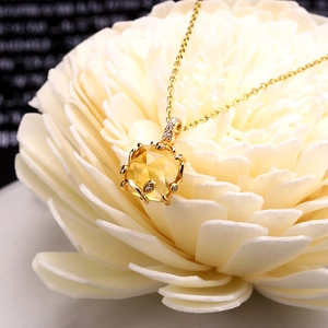 Dettaglio macro di un ciondolo in cristallo giallo quadrato con diamanti su un fiore