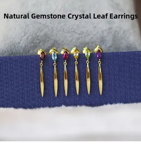 Macro detail of leaf drop earrings with multi-colored crystals on a dark blue display