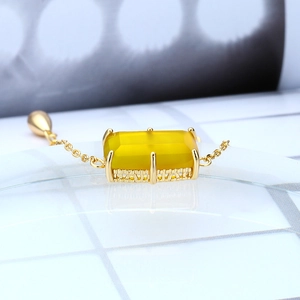 Macro shot of rectangular yellow chalcedony gemstone with hollow gold base on a bracelet