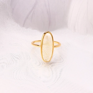 Vue macro d'une bague en argent S925 doré avec quartz rutilé ovale sur tissu blanc