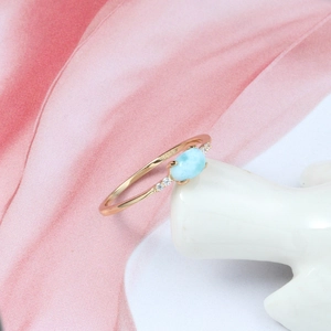 Macro detail of Larimar silver ring with zircon accents on a ceramic hand display