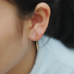 Close-up of leaf drop earrings with yellow marquise cut gemstone on model's ear