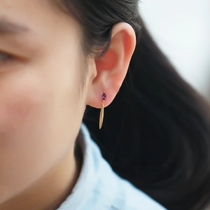 Detailed view of leaf drop earrings with marquise purple crystal on model ear