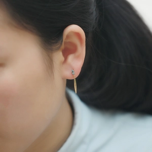 Macro shot of s925 silver leaf earring with marquise-cut blue gemstone on ear