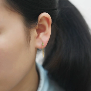 Macro shot of S925 silver leaf earring with pear-cut green gemstone and golden drop