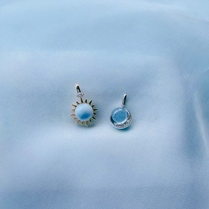 Detail van 925 zilveren zon- en maanhangers met larimar en blauwe topaas op blauwe zijde