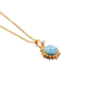 Detail van gouden zonne-hanger ketting met larimar steen en zirkoon accenten