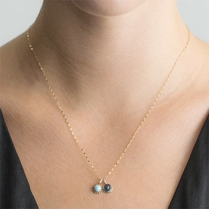 Gouden zon- en maan-hanger ketting met blauwe edelstenen op de hals getoond