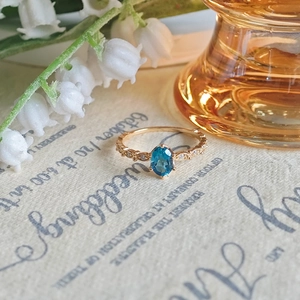 Dettaglio dell'anello in argento S925 dorato con topazio blu ovale e incisione vintage