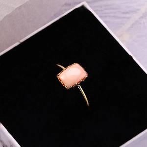 Détail de la pierre rose sertie dans un anneau doré festonné sur velours noir