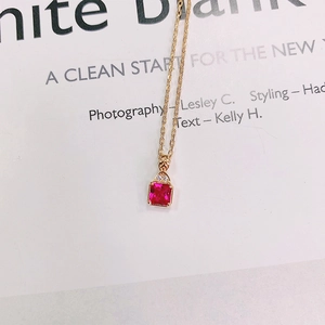 Detailed macro view of a square-cut red gemstone pendant on a dainty gold necklace chain