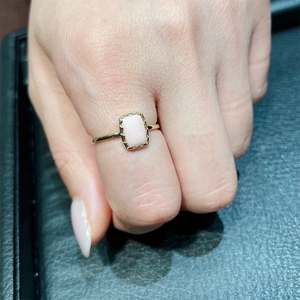 Vue détaillée d'une bague dorée avec pierre rose rectangulaire et bordure ciselée