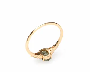 Macro detail of gold-plated silver ring with green stone and side zircon accents