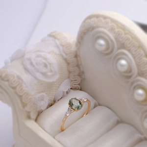 Makroansicht eines Rings mit grünem Rutilquarz und Zirkonia auf einem Vintage-Minisofa