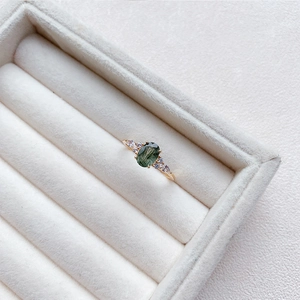 Nahaufnahme eines Rings mit ovalem grünem Nadelquarz, vergoldet mit Zirkonia-Akzenten