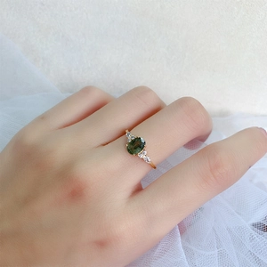 Nahaufnahme des vergoldeten 925er Silberrings mit grünem Edelstein und Zirkonia am Finger