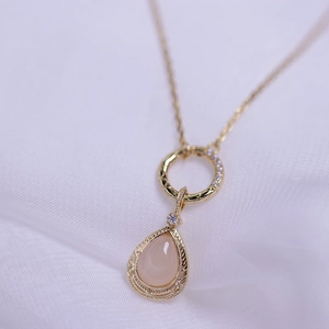 Detailansicht der Halskette mit rosa Tropfen-Edelstein und floraler Goldgravur