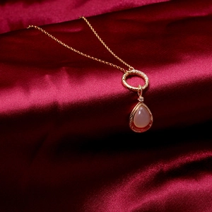 Detail einer Vintage-Goldkette mit birnenförmigem rosa Stein und Diamantkreis auf roter Seide