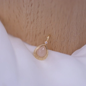 Makrodetail eines tropfenförmigen Anhängers mit rosa Edelstein und goldener Gravur
