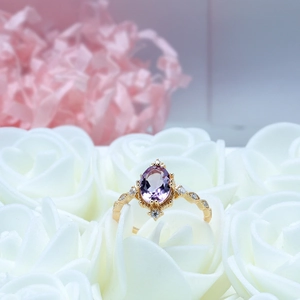 Dettaglio anello vintage in oro con ametista ovale e diamanti su petali di rosa