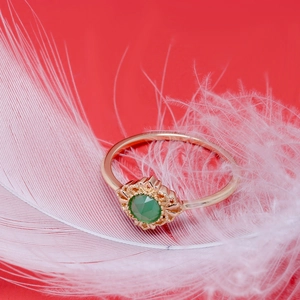 Macro shot of 14K gold plated silver ring with green agate on white feather background